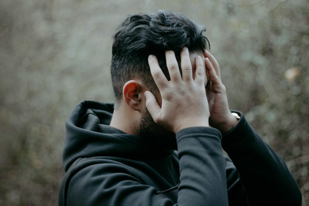 A man stands outdoors with his hands on his head, conveying stress and contemplation.
