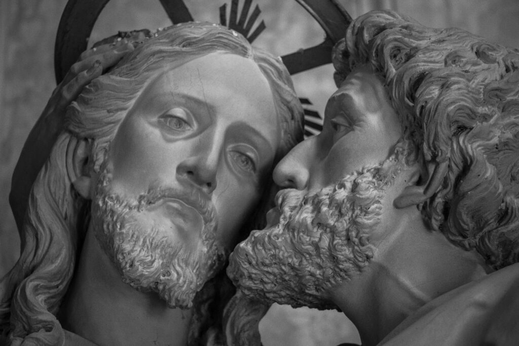 Close-up of a sculpture depicting the kiss of betrayal by Judas to Jesus in grayscale.
